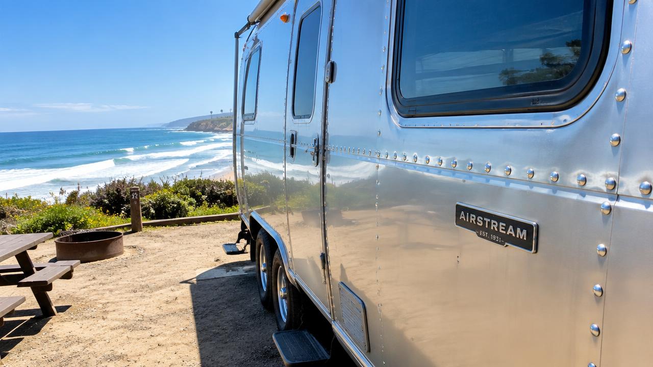 Airstream parked at a beach campground with ocean surf in the background