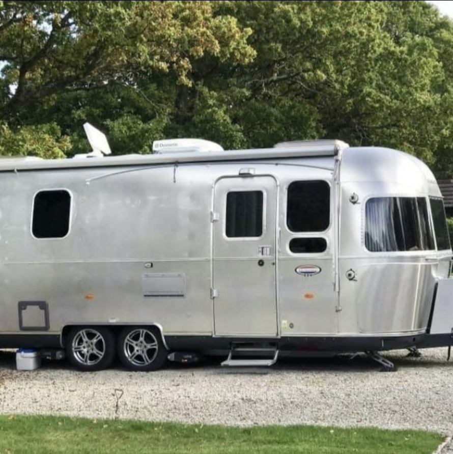 Side view of a modern Airstream travel trailer parked on gravel